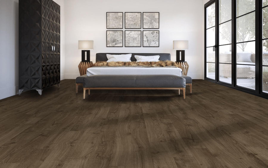 A modern bedroom with a large bed, two lamps on wooden bedside tables, abstract black and white wall art, dark wood floors, and large glass doors letting in natural light.