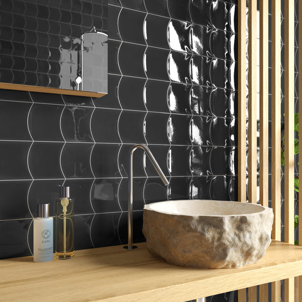 A modern bathroom vanity with a stone basin, sleek metal faucet, black wavy tile backsplash, and two bottles on a wooden countertop, with vertical wooden slats on the right side.