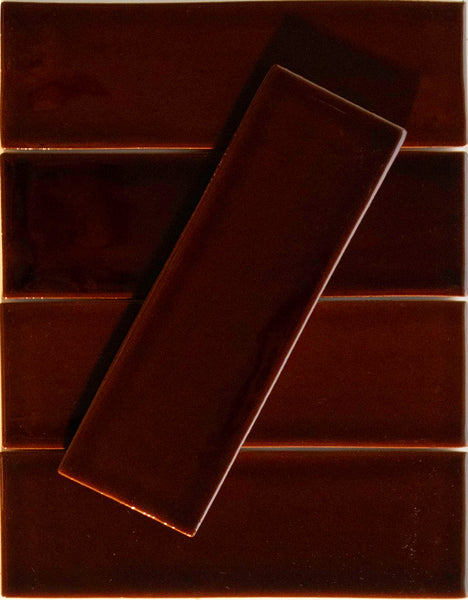 Five glossy Noir Crackle 2.5x8 Ceramic Tiles in Whiskey Neat are arranged horizontally, with one similar hand-dipped tile placed diagonally across the others to create a striking layered geometric pattern.