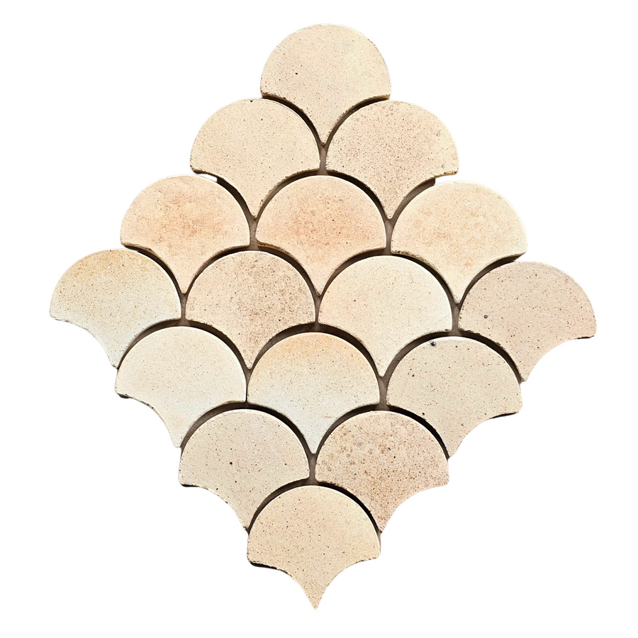 A mosaic of Atelier Clay Scale Mosaic Natural Stone tiles in a beige hue is arranged in a repeating fan or scallop pattern, creating a diamond-shaped layout on a white background.
