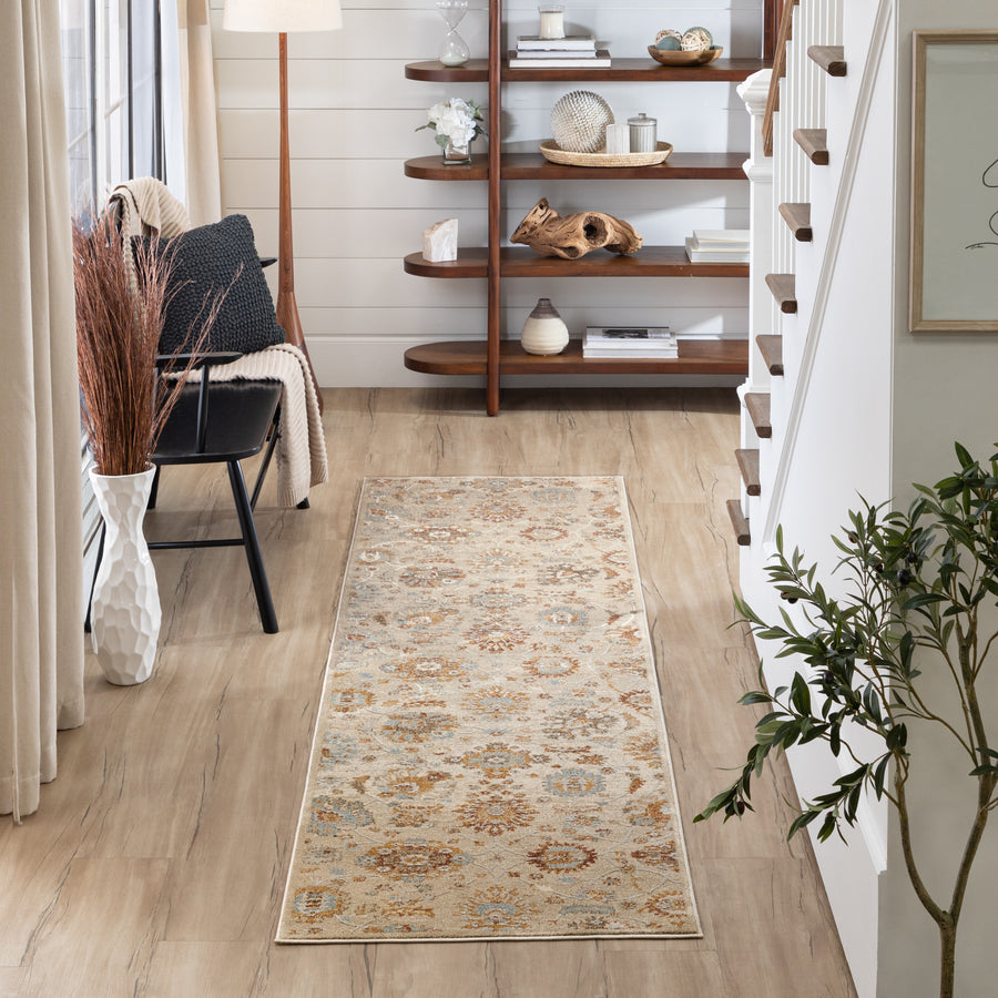 A cozy, modern entryway features a beige patterned runner rug, wooden floors, potted plant, black chair with pillow and throw, a floor lamp, and wooden shelves with decorative items beside a staircase.