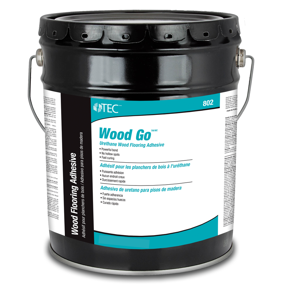 A large black pail labeled TEC Wood Go, a moisture cure urethane wood flooring adhesive, with product details and instructions in English, French, and Spanish on a white and teal label.