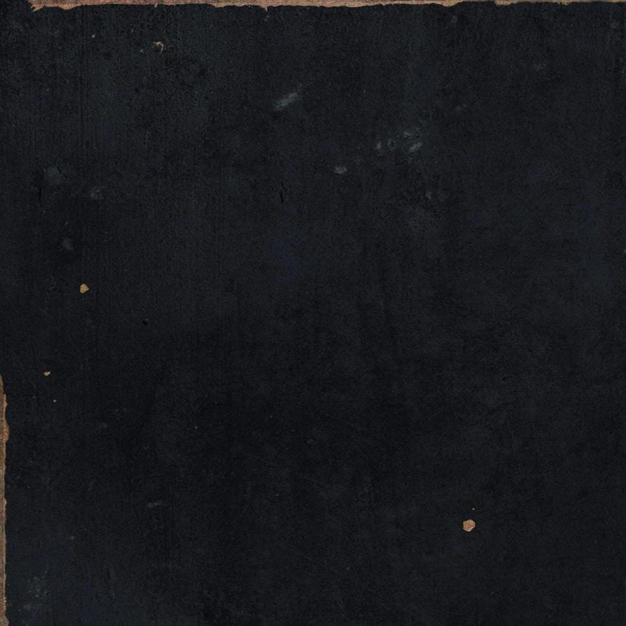 A worn, textured black surface with small brownish spots and rough, chipped edges, giving an aged, weathered appearance similar to an old book cover or piece of painted wood.