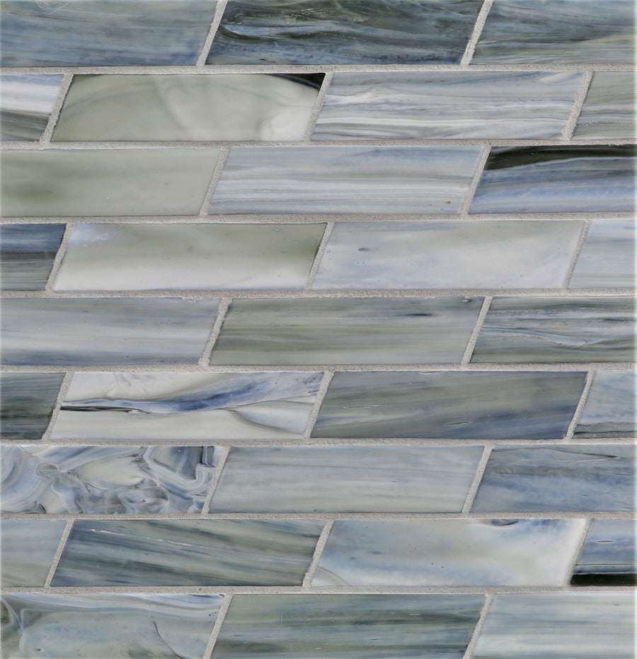 Close-up of a wall with Agate Dash Pisa Mosaic Glass Tile in a staggered layout, featuring rectangular glass tiles with swirling gray, blue, and white tones for a marbled look and subtle color variation.