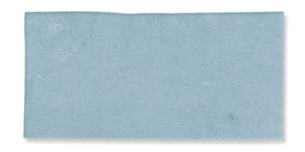 A rectangular, light blue rug or mat with a slight uneven edge on the top side, photographed against a white background.