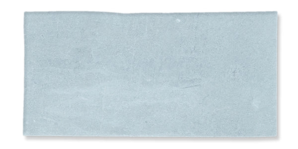 A rectangular, light blue tile with a slightly uneven surface and a soft, matte finish. The edges are straight with a subtle irregularity, and the color is uniform with faint variations.