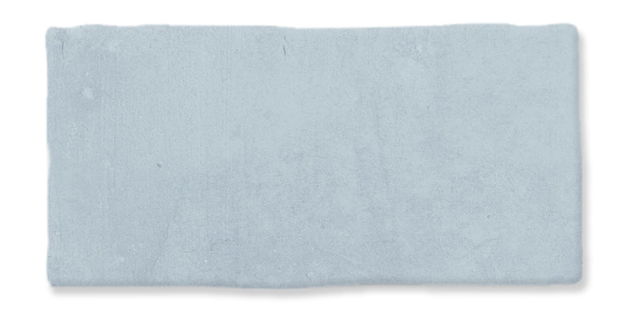 A rectangular, light blue ceramic tile with slightly uneven edges and a matte, textured surface.