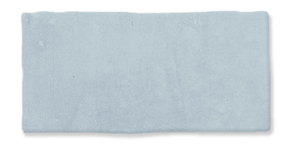 A rectangular, light blue ceramic tile with slightly uneven edges and a matte, textured surface.