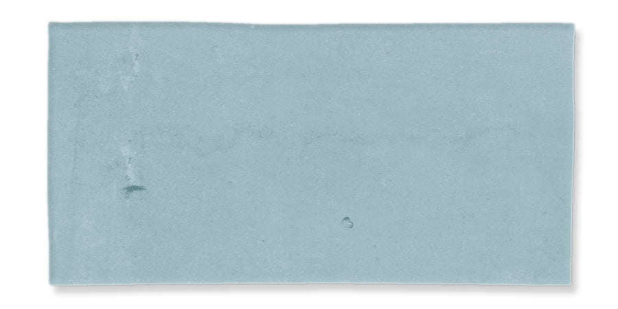 A rectangular, light blue tile with a slightly uneven surface texture and subtle variations in color.