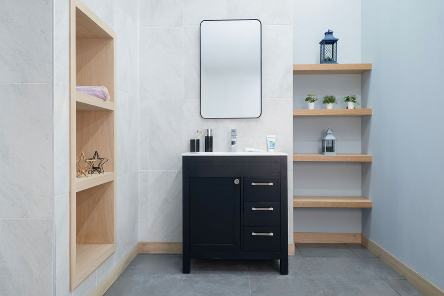 A modern bathroom showcases the Aria 30" Vanity with a white sink, rectangular mirror, light wood shelves with decor on each side, and light gray tiled walls and floor.