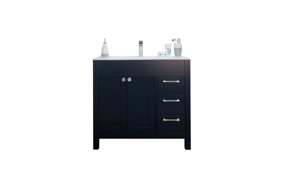 A black bathroom vanity with two doors and three drawers, topped with a white countertop holding a soap dispenser, toothpaste, toothbrushes, and a few toiletry items, isolated on a white background.