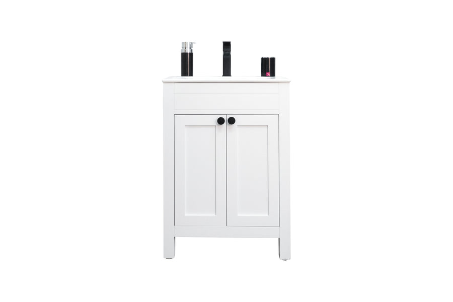 A white bathroom cabinet with two doors and black knobs, standing on four legs. On top are several black and silver toiletry bottles arranged neatly.