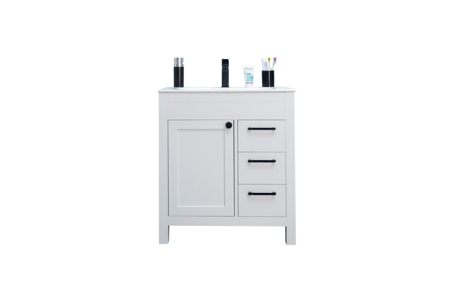 A white bathroom vanity with one cabinet and three drawers, featuring black handles. On top are toiletries, including bottles, a tube, and a cup holding toothbrushes, all isolated on a white background.