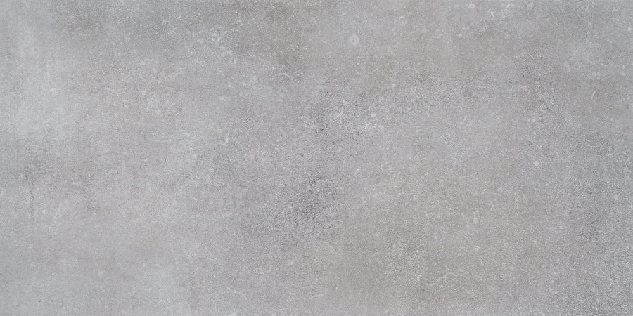 A close-up of the Ardennes 12" x 24" Tile in Cliff—a smooth, light gray surface with subtle speckles and texture, perfect for accent walls or statement floors.
