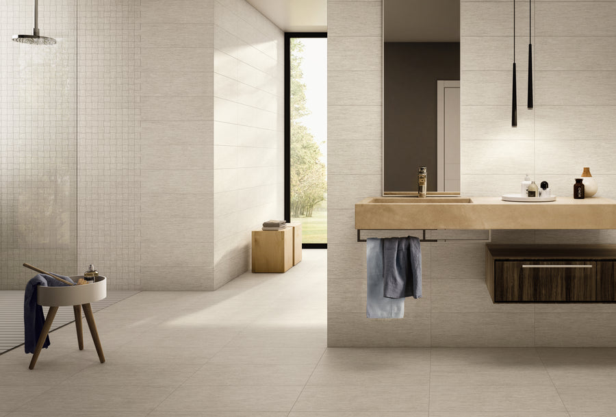 Modern bathroom with beige tiles, floating sink, wooden cabinet, and a large window letting in natural light. Minimalist decor includes a stool with towels and hanging pendant lights. Shower area visible on the left.