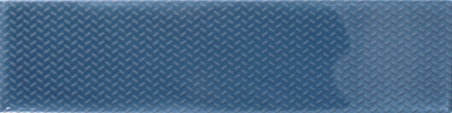 The Gradient Décor 3"x12" Subway Tile in Indigo Gloss features a repeating diagonal chevron pattern, ideal for accent walls or backsplashes to create a textured, three-dimensional effect.
