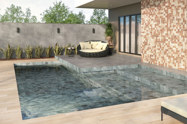Modern backyard with a small pool, stone tile steps, a sunken seating area with a round cushioned sofa, potted plant, a tiled wall, and green plants along a concrete privacy wall.