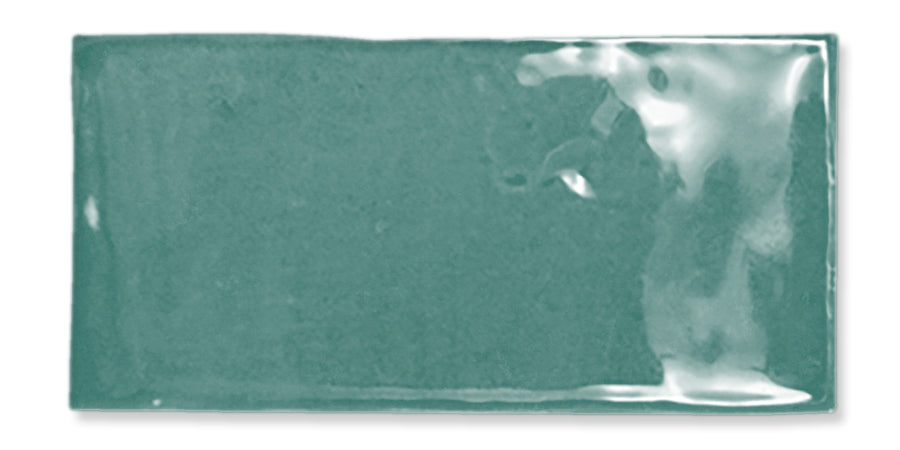 A rectangular, glossy teal ceramic tile with a slightly uneven surface and subtle texture.