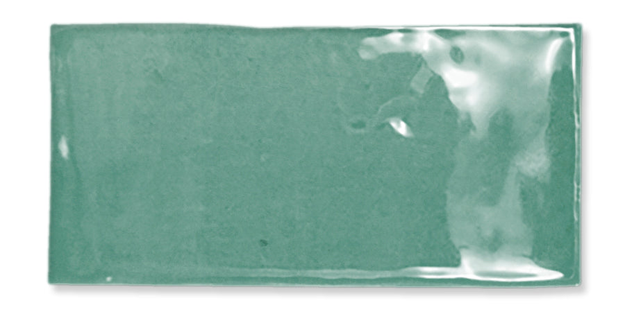Rectangular, glossy, light green ceramic tile with a slightly uneven surface and smooth edges, reflecting light in the top right corner.
