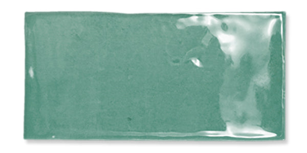 Rectangular, glossy, light green ceramic tile with a slightly uneven surface and smooth edges, reflecting light in the top right corner.