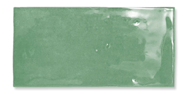 A rectangular, glossy green ceramic tile with a smooth surface and slightly uneven texture, reflecting light in some areas.