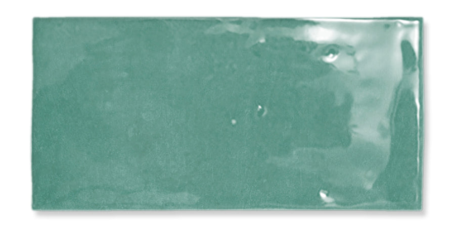Glossy rectangular ceramic tile in a muted green color, shown against a white background. The tile surface has a smooth, slightly reflective finish with subtle texture and minor imperfections.