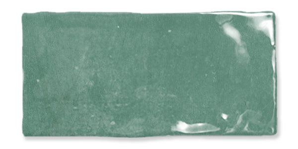 A single rectangular, glossy green ceramic tile with uneven edges and a slightly textured surface. Light reflections are visible on the tiles upper right area.