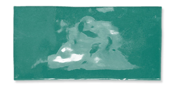 A rectangular, glossy teal ceramic tile with a slightly uneven surface and some lighter and darker patches creating a marbled effect.