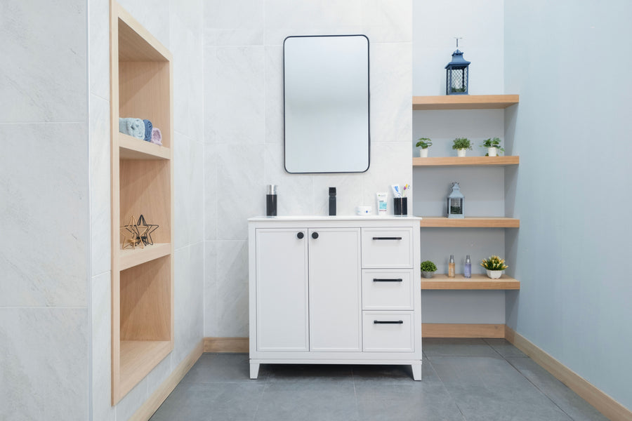 A modern bathroom features the Frame 36" Vanity, a rectangular mirror, and shelves displaying toiletries, plants, and decor. Light-colored walls and a sleek gray tile floor complete the contemporary look.