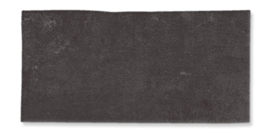 A rectangular, dark gray stone or tile with a slightly rough texture and uneven upper edge, set against a white background.