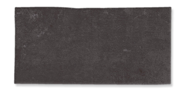 A rectangular, dark gray stone or tile with a slightly rough texture and uneven upper edge, set against a white background.