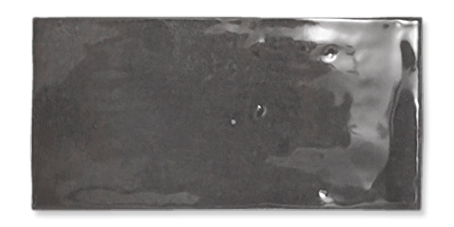 Glossy rectangular black ceramic tile with subtle reflections and slight surface imperfections, isolated on a white background.