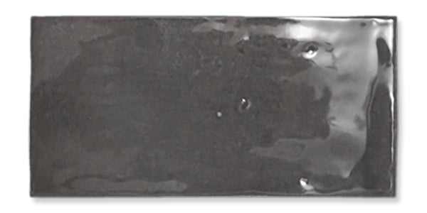 Glossy rectangular black ceramic tile with subtle reflections and slight surface imperfections, isolated on a white background.
