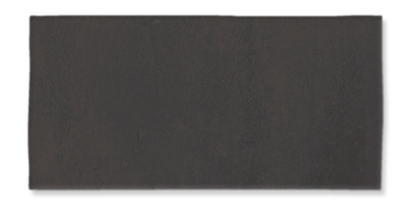 A rectangular, dark gray tile with a matte finish, set against a white background. The surface appears smooth with subtle variations in shading.