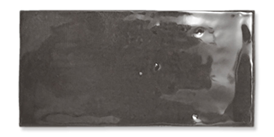 A shiny, rectangular, dark gray ceramic tile with slightly uneven surface texture and glossy finish, shown against a white background.
