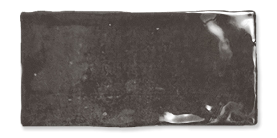A rectangular, glossy black ceramic tile with slightly uneven edges and subtle reflections on its surface.