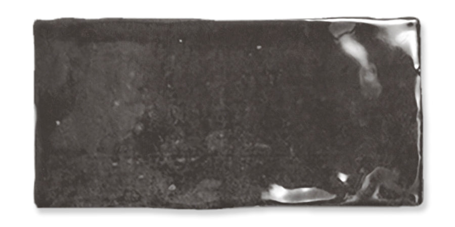 A rectangular, glossy black ceramic tile with slightly irregular edges and a reflective surface.