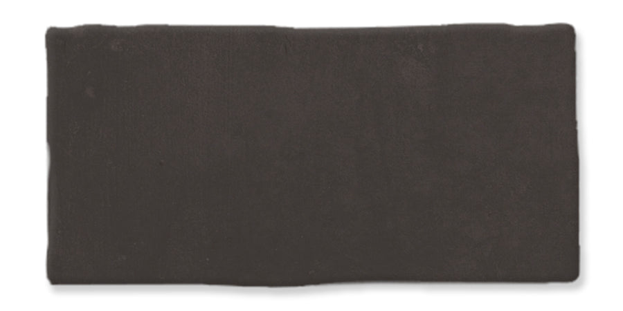 A rectangular piece of solid, dark brown clay or modeling material with slightly uneven edges, set against a white background.