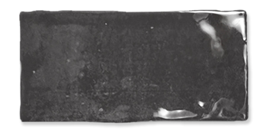 A rectangular, glossy, black ceramic tile with slightly uneven edges and reflective spots on the surface.