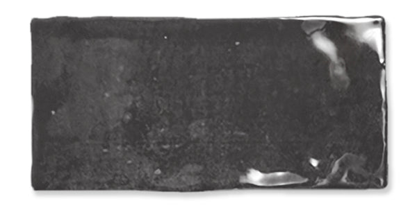 A rectangular, glossy, black ceramic tile with slightly uneven edges and reflective spots on the surface.