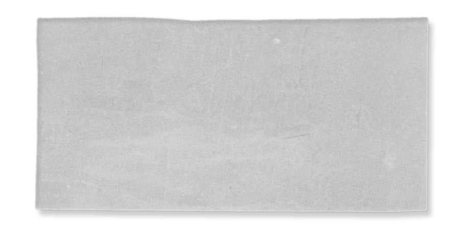 A rectangular, flat, light gray stone tile with a slightly uneven top edge and a smooth surface, isolated on a white background.