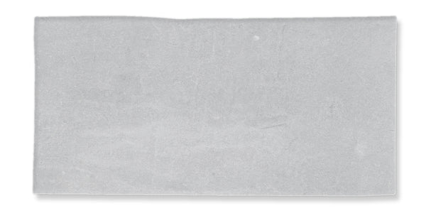 A rectangular, flat, light gray stone tile with a slightly uneven top edge and a smooth surface, isolated on a white background.