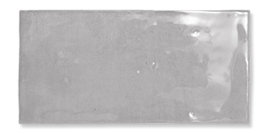 A shiny, rectangular gray ceramic tile with a slightly uneven glossy surface and subtle texture.
