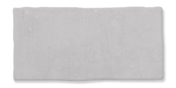 A rectangular, slightly uneven light gray stone or concrete tile with a rough texture and subtle surface variations.