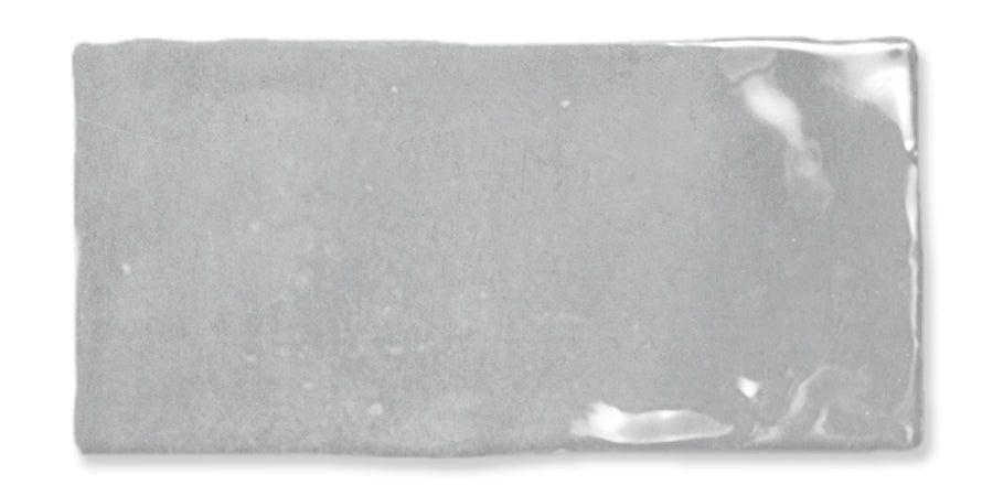 A rectangular, glossy light gray ceramic tile with uneven edges and a slightly reflective surface.