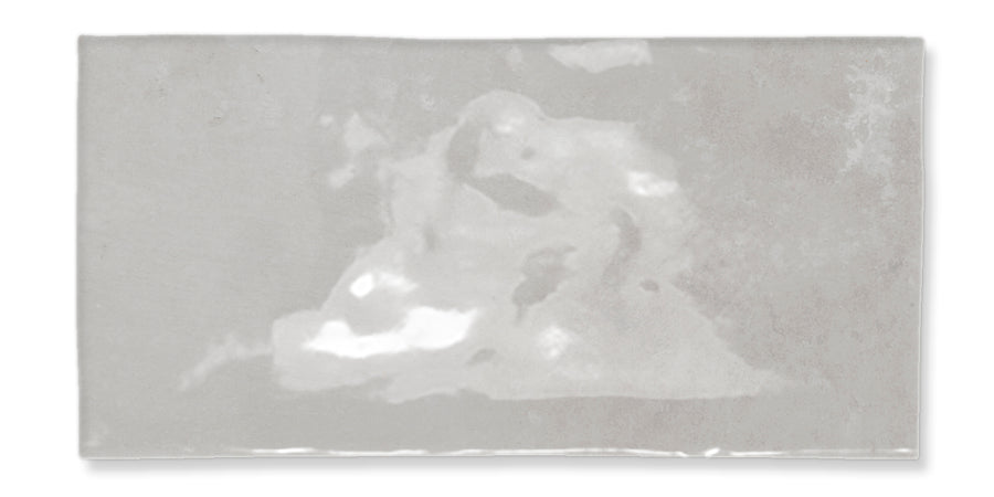 A rectangular, light gray tile with a slightly uneven surface and subtle white and darker gray marbled patterns.