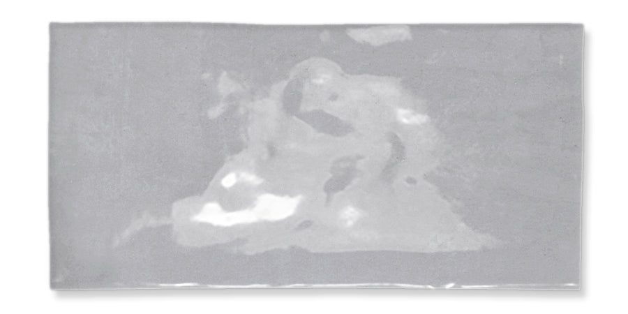 A rectangular, shiny silver object with subtle, abstract light and dark patches creating an uneven, reflective surface. The background is white.