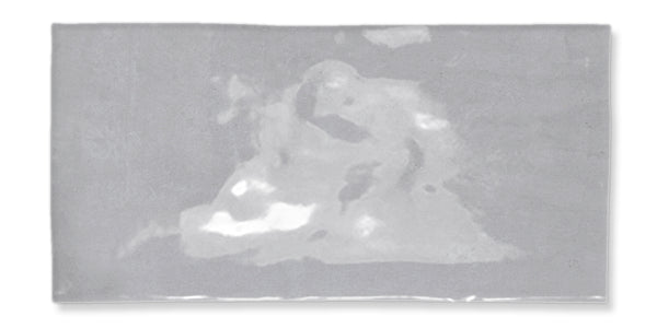 A rectangular, shiny silver object with subtle, abstract light and dark patches creating an uneven, reflective surface. The background is white.