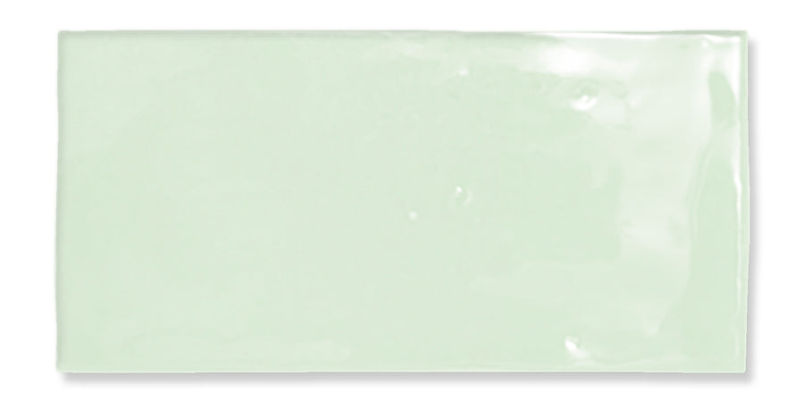 A glossy, rectangular, light mint green tile with a smooth surface and slightly uneven edges, set against a white background.
