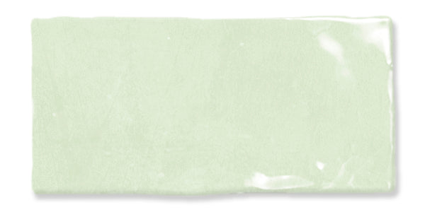 A rectangular, glossy, light green ceramic tile with slightly uneven edges and a smooth surface reflecting light.